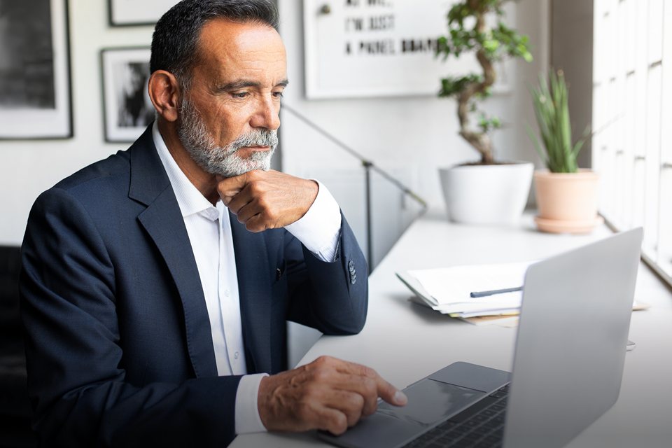 A man in a suit is working at a laptop