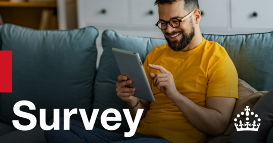 A man working on an electronic device on a sofa. Text reads: Survey
