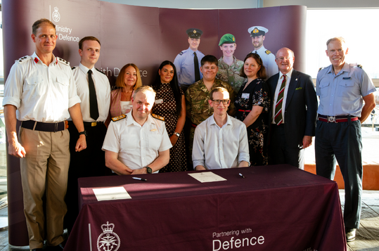 Andy King signs the Armed Forces Covenant in the Senedd, surrounded by colleagues from Companies House and members of the armed forces