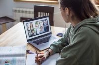 young lady sitting at laptop in home at virtual meeting