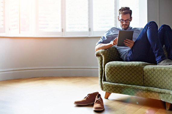 Man reading tablet on a sofa at home