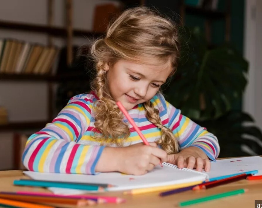 Little girl drawing a picture of her school