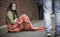A young woman sleeping on the street; people walk past
