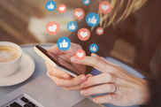 Woman using a mobile phone, a cloud of 'like' and 'favourite' icons rising out of it 