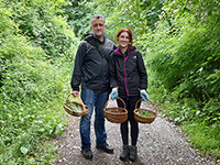 2 people on a countryside path holding foraging baskets