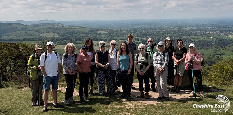 Group of walkers in the countryside looking at the camera with the Cheshire Plain in the background