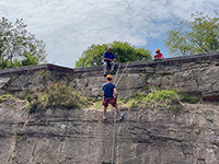 Adult abseiling down rockface