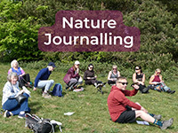 People sat on the grass with 'Nature Journalling' in the foreground