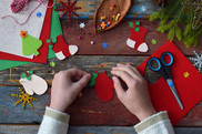 Aerial view of child's hands with Christmas craft materials and scissors 