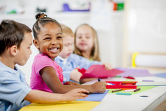 Young children painting, laughing and smiling