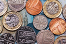 Coins of lots of different values lie flat against a ten pound note