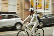 Woman cycling past cars on a street