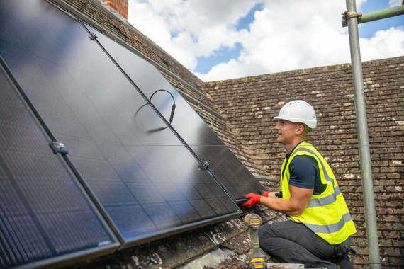 Man installing solar panels on roof