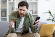 Stressed man holding his phone and credit card