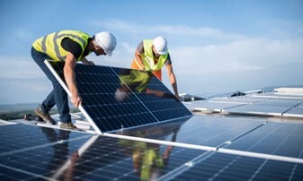 Two installers installing solar panels on a roof