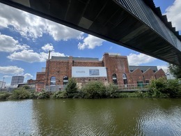 A view of Daimler Powerhouse with a water and a bridge in front of it