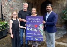 Four people standing outside Cheylesmore Manor with a Win a Wedding sign