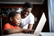 A child is online with his father supervising