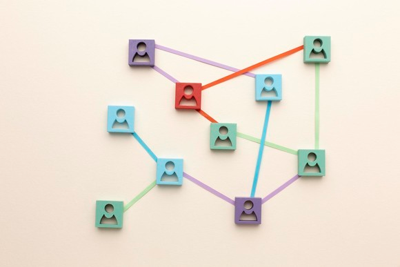 Digital 3-D image of a collection of different coloured profile icons and interconnecting lines between them, against a light cream background