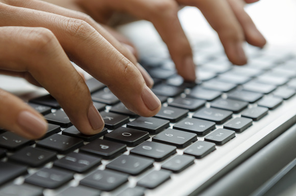 Hands typing on a laptop keyboard.