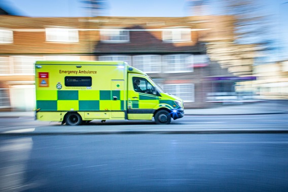 Photograph of an ambulance in motion - the background is blurred to suggest it's moving quickly.