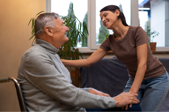 Image by Freepik shows an older man in a wheelchair smiling with a visitor