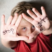 young boy with hands held up with 'stop bullying' written on hands