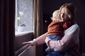 child poverty - mum holding young child hand over radiator