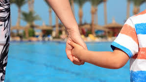 adult holding childs hand near swimming pool