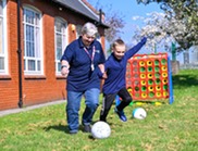 Family Hub worker playing football with boy
