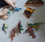 child surrounded by toy dinosaurs