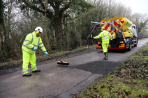 Jetpatcher machine with two council operatives repairing potholes.