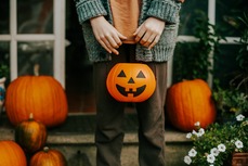 Child holding a pumpkin in front of a doorway