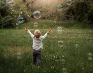 Boy playing with bubbles in a field