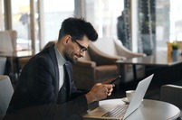 Man sitting in a cafe with a mobile phone and laptop