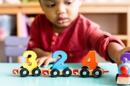 Child with colourful numbers each on a train carriage