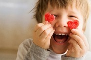 Child holding two heart in front of their face