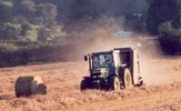 A tractor in a field in late summer baling hay