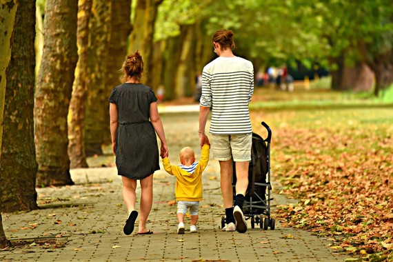 Mother and father walking with toddler and pram along a pavement