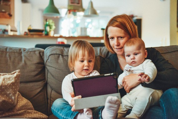 Mother with two young children sat on sofa with an ipad