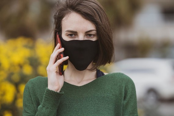 Woman wearing a black face covering using a mobile phone
