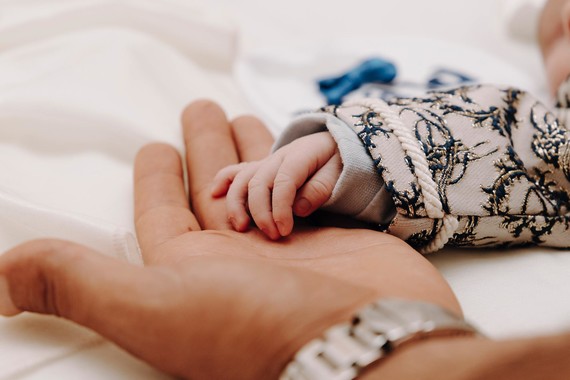 newborn baby's hand resting on adult hand