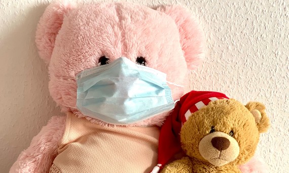 two teddy bears with one wearing a face mask