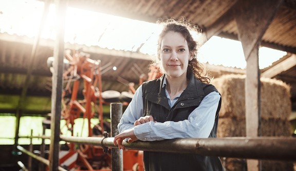 Female farmer leaning on a metal fence in a barn