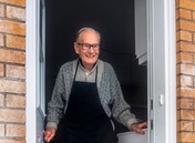 An elderly person standing in a doorway