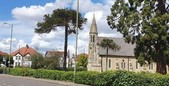 An image of a church with trees and hedges