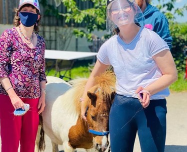 Two girls standing next to a pony.