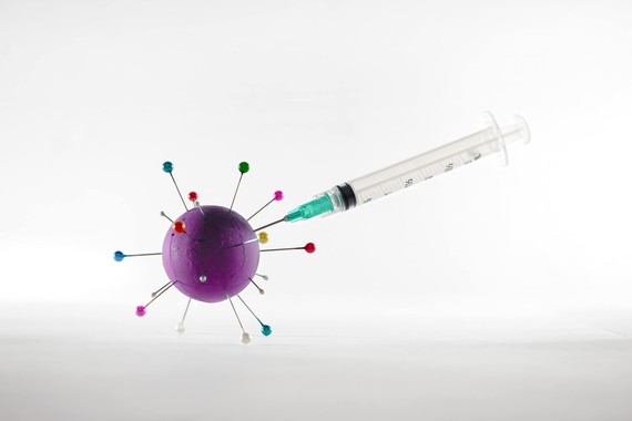 A syringe going into a rubber ball which has pins