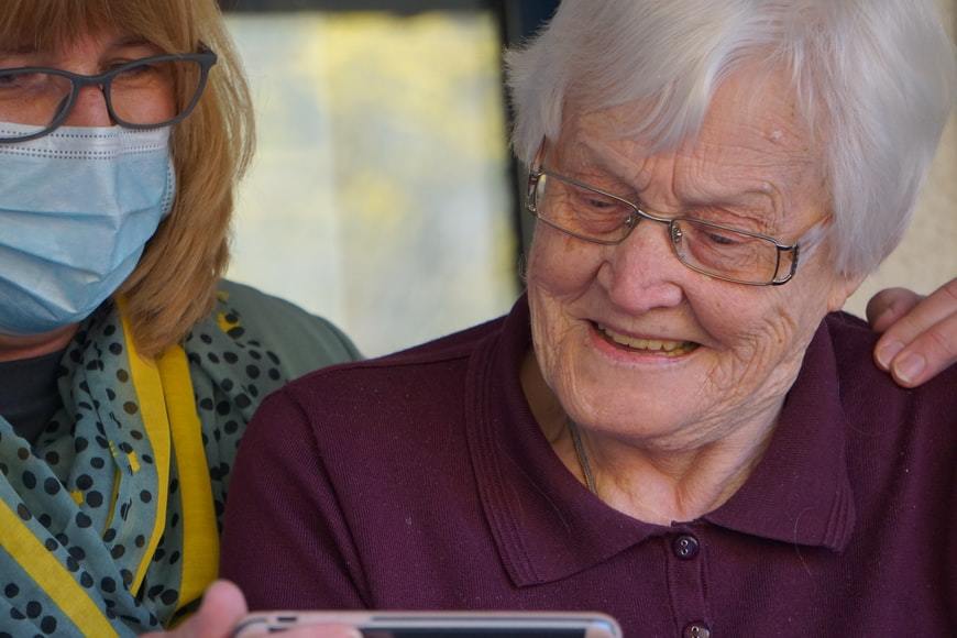 older woman and carer looking at a mobile