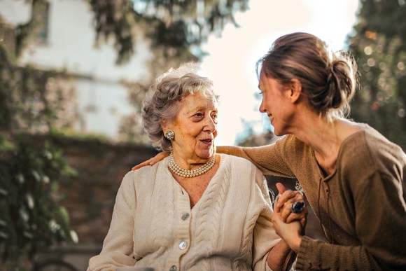 Grown up daughter visiting her mother in the garden at a care home